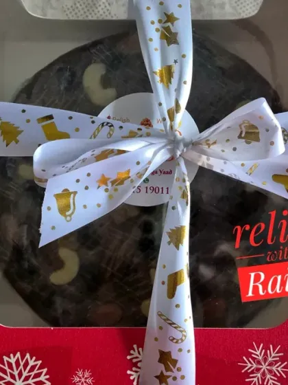 A beautifully packaged Christmas Plum Cake, ready for gifting. This rich, boozy fruitcake is loaded with rum-soaked dried fruits and nuts, and blended with authentic spices for a truly festive flavor.