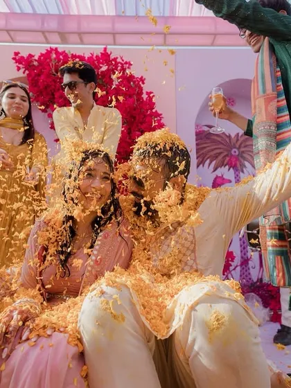 A shower of flower petals for the happy couple during their Haldi. The decor is kept bright and sunny with pink and yellow, reflecting the joyful mood of the ceremony.