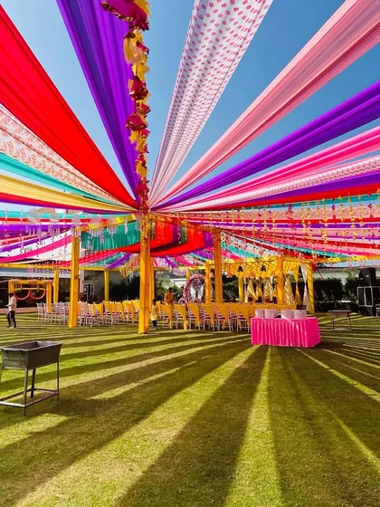 A wide-angle shot of this large-scale Haldi setup, with a vibrant canopy of multi-colored drapes covering the entire guest seating area.