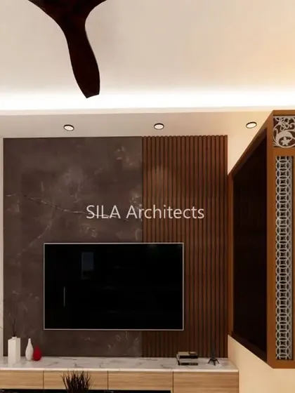 Another angle of the JP Nagar living room, focusing on the TV wall which combines dark marble and fluted wood panels.