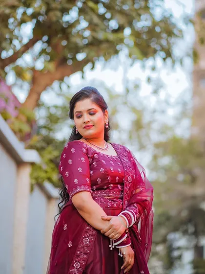 A beautiful solo portrait of the bride in her elegant maroon gown, taken outdoors after her church wedding. Her serene expression captures a moment of quiet happiness.