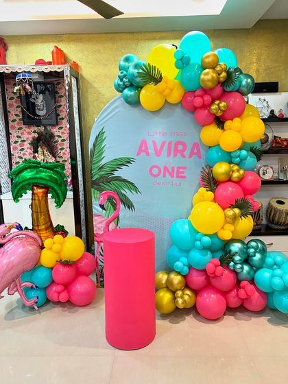 This is a duplicate of ID 41, 112. A vibrant tropical flamingo theme for a first birthday at home. This setup includes a personalized backdrop, a colorful balloon garland, and a flamingo prop.