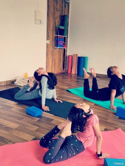 These pre-teens are exploring a deeper variation of Eka Pada Rajakapotasana, or one-legged king pigeon pose. Using blocks for support helps them open their backs and shoulders safely.