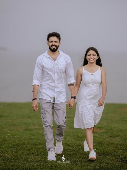 A confident walk together with the sea in the background. The coordinated white and grey outfits create a clean and modern look.