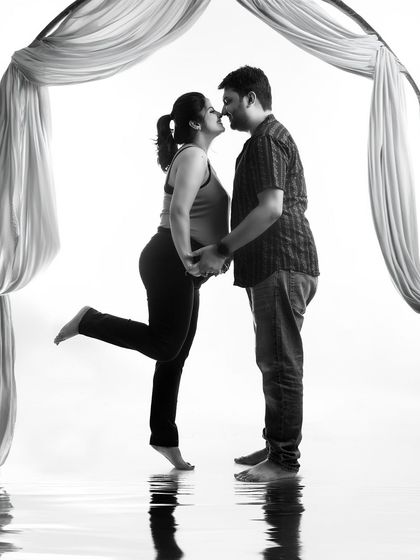 A playful and romantic black and white silhouette. The 'almost kiss' pose and the water reflection effect create a fun and artistic image of the couple's connection.