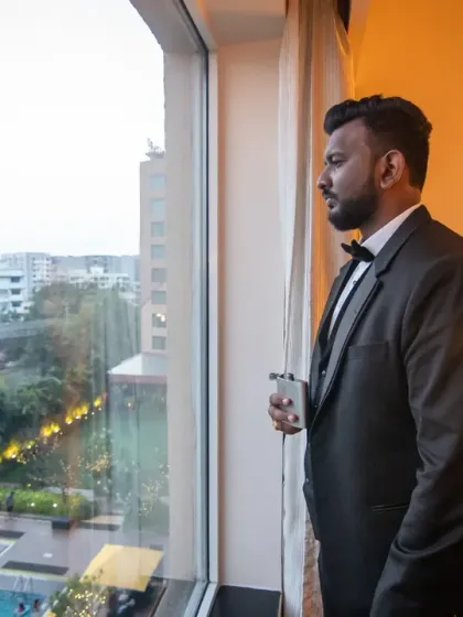 The groom looking out the window, a quiet moment of reflection before the wedding reception begins.