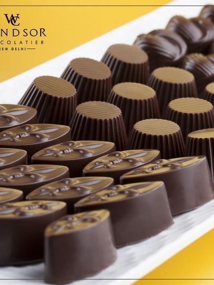 A platter showcasing the variety of shapes and finishes in our dark chocolate collection. From fluted cups to ovals with custom imprints, each piece is crafted to be a small work of art.