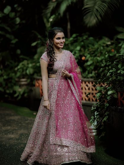 A full-length portrait of the bride-to-be in her stunning pink and silver lehenga, looking radiant and happy.
