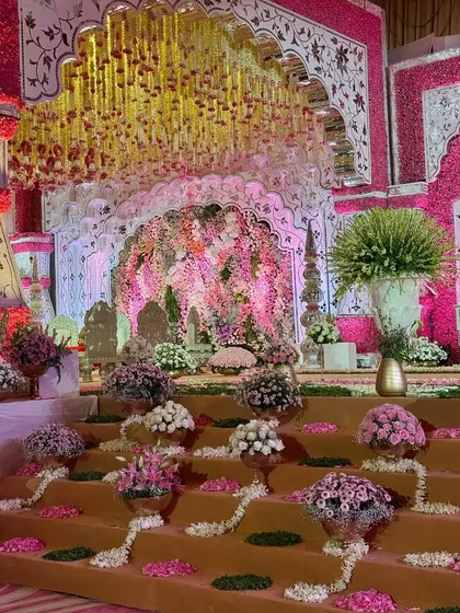 A view of the mandap stairs, adorned with floral arrangements in copper vases and scattered petals. This detail ensures that every part of the wedding stage is a spectacle of beauty.
