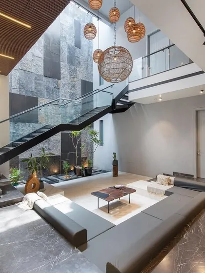 A perspective of the sunken lounge at Casa Acentuada, showing the interplay of natural stone, smooth marble, and custom furniture. A dedicated niche for religious idols is integrated seamlessly into the design.