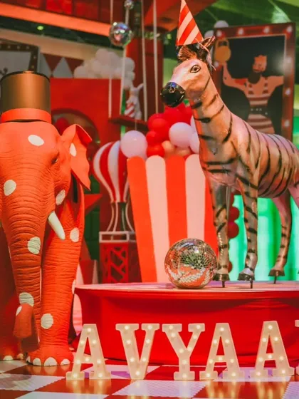 Custom props like this polka-dotted elephant and striped zebra are key elements of my circus theme. The light-up marquee letters spelling 'AVYAAN' add a personalized, celebratory touch to the decor.