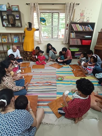 A full view of the room during a paper flower craft session. Everyone finds a comfortable spot to sit and create.