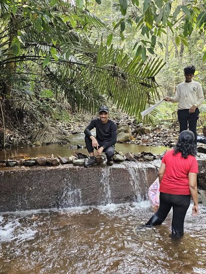 Crossing a small stream in the forest, a common and fun part of the Ulavi trek.