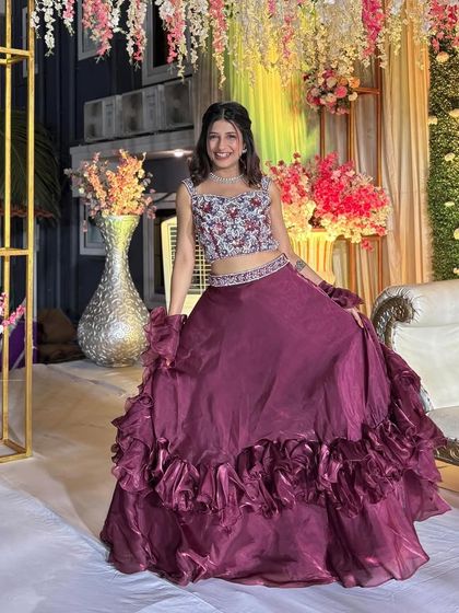 This outfit combines a traditional handcrafted blouse with a modern, ruffled organza skirt, showcasing the best of fusion wear. It’s perfect for dancing and celebrating in style.