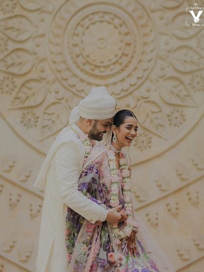 A moment of pure, uninhibited laughter. This candid shot captures the joy and friendship between the couple, set against a beautifully carved wall.