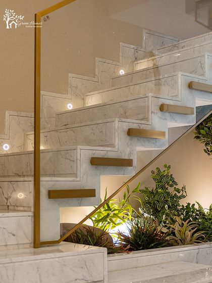 A close-up view of an under-staircase installation where light green foliage contrasts with the clean white marble. Spotlights are strategically placed to mimic sunlight and bring the artificial plants to life.