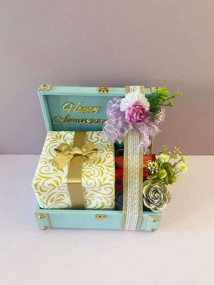 An anniversary gift hamper in a beautiful pastel blue trunk. The gifts inside are elegantly wrapped, making the unboxing experience extra special.