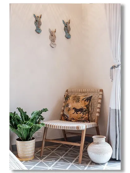 A quiet corner in a Goan villa, styled with a woven chair, a plant in a jute basket, and decorative zebra heads on the wall. The look is bohemian, eclectic, and inspired by travel.