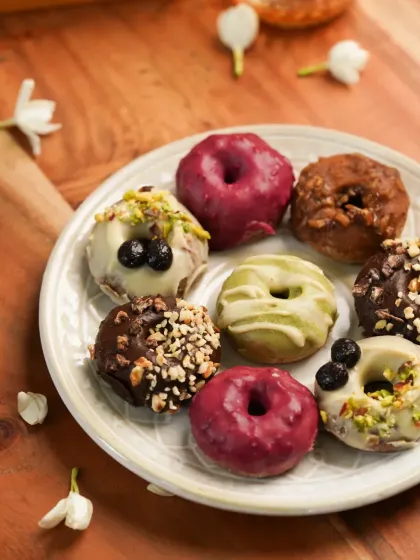 A plate of colorful and assorted doughnuts, styled with jasmine flowers for a festive yet contemporary look.