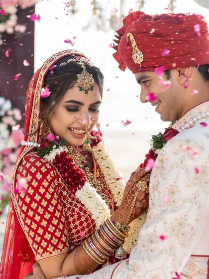 A happy, candid moment between the newly married couple, surrounded by flower petals. This is the pure, unfiltered joy we strive to document.