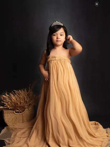 A fine art portrait with a regal feel. The flowing golden gown and classic tiara make her look like a little goddess.