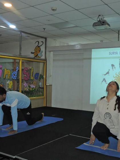 Instructors lead a Surya Namaskar (Sun Salutation) session on stage, guiding participants through the yoga sequence.