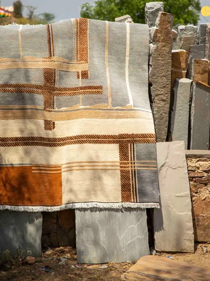 A rug from the Elemental Collection displayed against a backdrop of raw stone, highlighting the connection between our architectural materials and the textile designs.