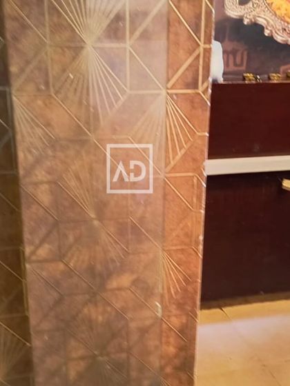 A close-up of the gold geometric wallpaper installed on a pillar in a hotel. This shows how wallpaper can be used to wrap around architectural features for a cohesive design.