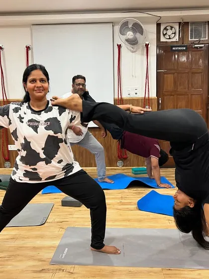Partner yoga doesn't always have to be perfect. This fun shot captures a moment of laughter and playfulness as two students work on a combined pose.