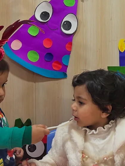 A friend helps the birthday girl with her cake, a sweet moment of caring.