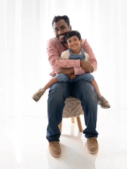 A happy and relaxed portrait of a father and his son. The genuine smiles and comfortable pose capture the easy bond between them.
