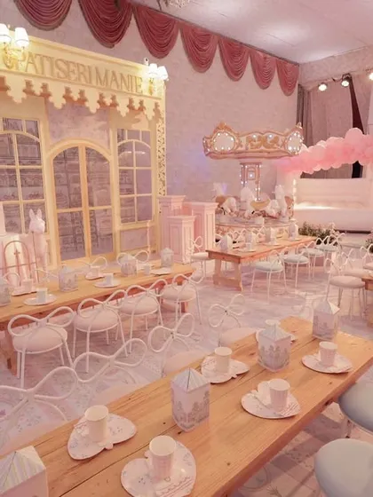 A whimsical Parisian patisserie theme brought to life for a child's birthday party. This immersive setup includes custom-built facades, soft pink florals, and elegant café-style seating for a truly magical experience.
