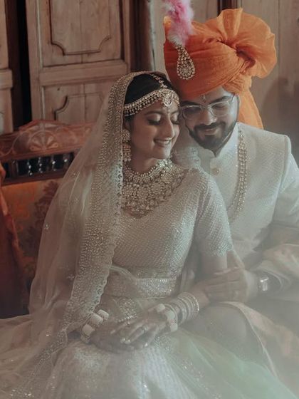 A soft, dreamy portrait of the couple seated together. The light flare adds a touch of magic, making the moment feel ethereal and romantic. This is a perfect example of a fine art wedding portrait.