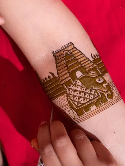 A work-in-progress shot showing the creation of a temple and elephant motif. This highlights the precision required to bring these grand traditional symbols to life in henna.