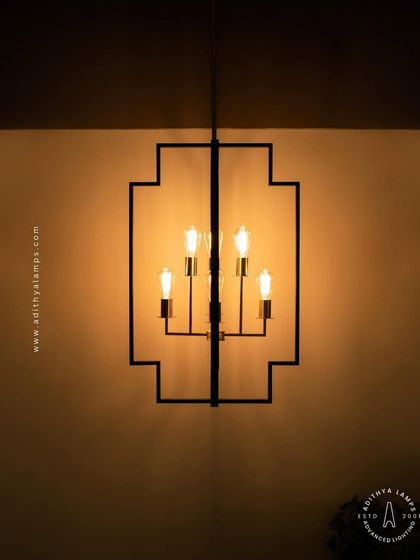 Inspired by Art Deco design, this hanging fixture features a strong geometric black frame with exposed vintage-style filament bulbs. The combination of black and warm gold tones provides a sophisticated, retro feel for dining areas or entryways.