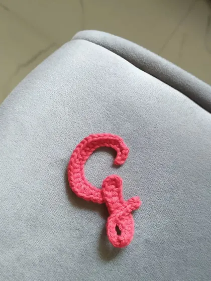 The calligraphy letter 'G' in the same pretty coral color.