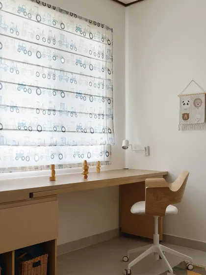 A close-up of the kids' room, showing the playful tractor-patterned roman blinds and the custom-designed, openable study desk.