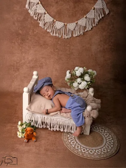 Beyond simple wraps, I offer creative, themed setups like this charming boho-inspired scene. This little gentleman is peacefully dreaming on a miniature bed, showcasing the variety of props available for your baby's shoot.