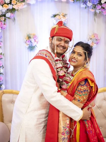 A warm embrace on the wedding stage, surrounded by beautiful floral decorations.