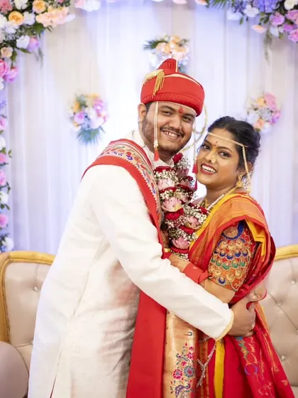 A warm embrace on the wedding stage, surrounded by beautiful floral decorations.