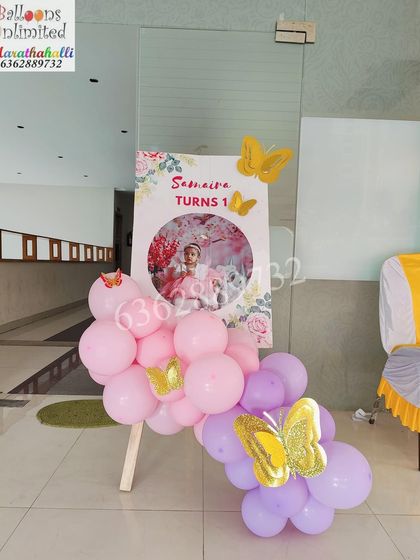 A personalized welcome sign for Samaira's first birthday, decorated with pink and purple balloons and butterfly accents.