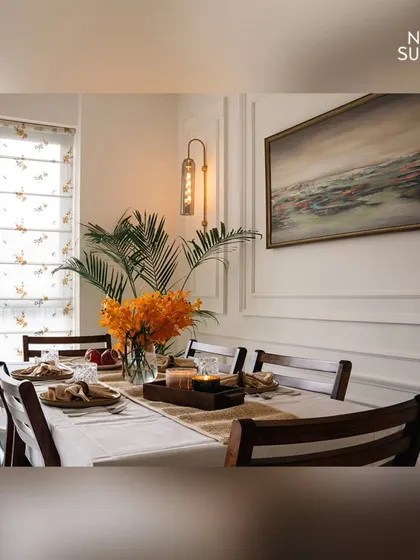 A side view of the dining setup, showing the elegant Roman blinds that filter natural light beautifully. The combination of dark wood chairs, a crisp white tablecloth, and warm lighting creates an intimate and refined dining experience.