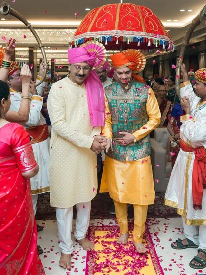The groom's grand entrance with his father under a traditional umbrella.