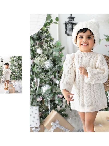 A big, bright smile for the holiday season. This little one's joy is infectious in her cozy white outfit against the snowy Christmas tree backdrop.