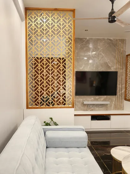 The geometric gold-finished partition adds a decorative element while maintaining an open feel between the foyer and the living area.