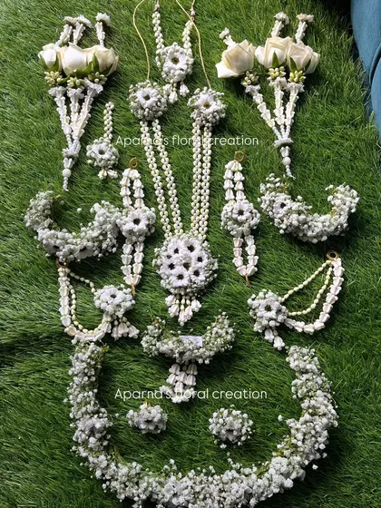 A complete baby shower set made with baby's breath and white roses. This set includes a tiara, necklace, earrings, haath phool, and bajuband.