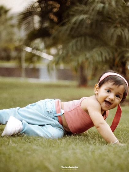 A baby girl enjoys crawling on the grass during a relaxed outdoor family session.