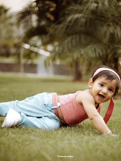 A happy baby girl enjoys some tummy time on the grass during an outdoor session. We let little ones explore and play, capturing their natural curiosity and joyful expressions.
