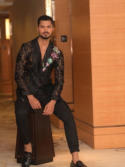 A seated pose in the same lace blazer, exuding confidence and style in an elegant indoor setting.