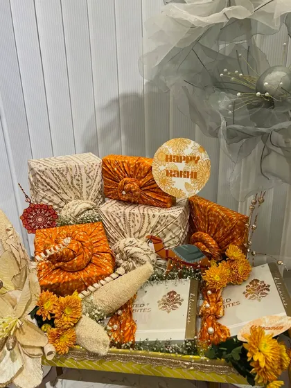 Another view of the traditional Rakhi setup, highlighting the fabric-wrapped gifts and floral arrangements.